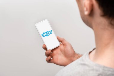 Kiev, Ukrayna - 16 Mayıs 2019: gri üzerinde izole skype uygulaması ile akıllı telefon kullanarak adam kırpılmış görünümü