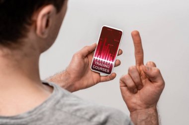 ticaret kursları uygulaması ile akıllı telefon kullanarak ve orta parmak gösteren adam kırpılmış görünümü, gri izole