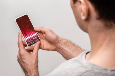 ticaret kursları uygulaması ile akıllı telefon kullanarak adam kırpılmış görünümü, gri izole