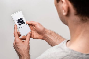 Kiev, Ukrayna - 16 Mayıs 2019: gri üzerinde izole uber uygulaması ile akıllı telefon kullanan adam kırpılmış görünümü