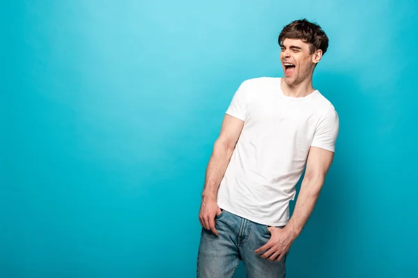 Jovem Alegre Rindo Enquanto Olha Para Fundo Azul — Fotografia de Stock