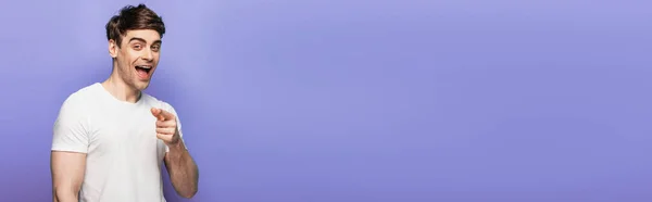 Панорамный Снимок Веселого Молодого Человека Указывающего Пальцем Камеру Синем Фоне — стоковое фото