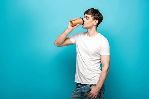 Bonito Jovem Bebendo Café Para Olhando Para Longe Fundo Azul — Fotografia de Stock