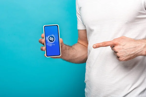 乌克兰 2019年5月16日 裁剪视图的人指着智能手机与Shazam应用程序 隔离在蓝色 — 图库照片