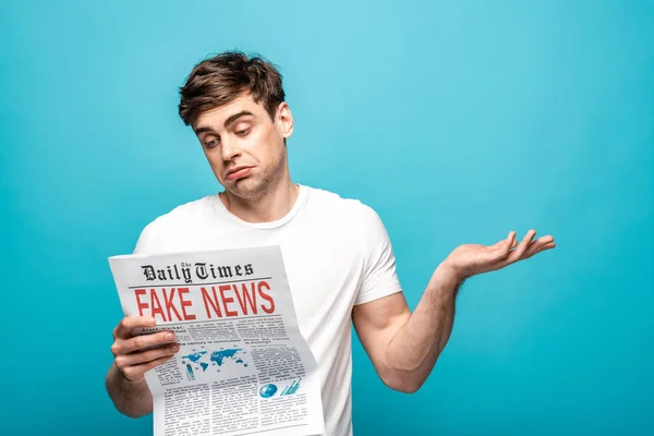 Discouraged Young Man Showing Shrug Gesture While Reading Newspaper Fake — Stock Photo, Image