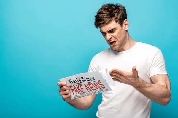 Joven Insatisfecho Leyendo Periódico Con Noticias Falsas Sobre Fondo Azul — Foto de Stock