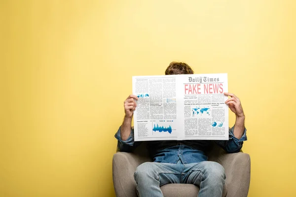 Young Man Sitting Armchair Reading Newspaper Fake News Yellow Background — Stock Photo, Image