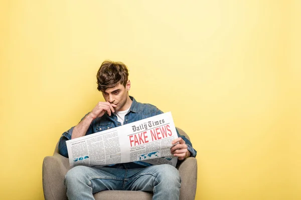 Attentive Young Man Sitting Armchair Reading Newspaper Fake News Yellow — Stock Photo, Image