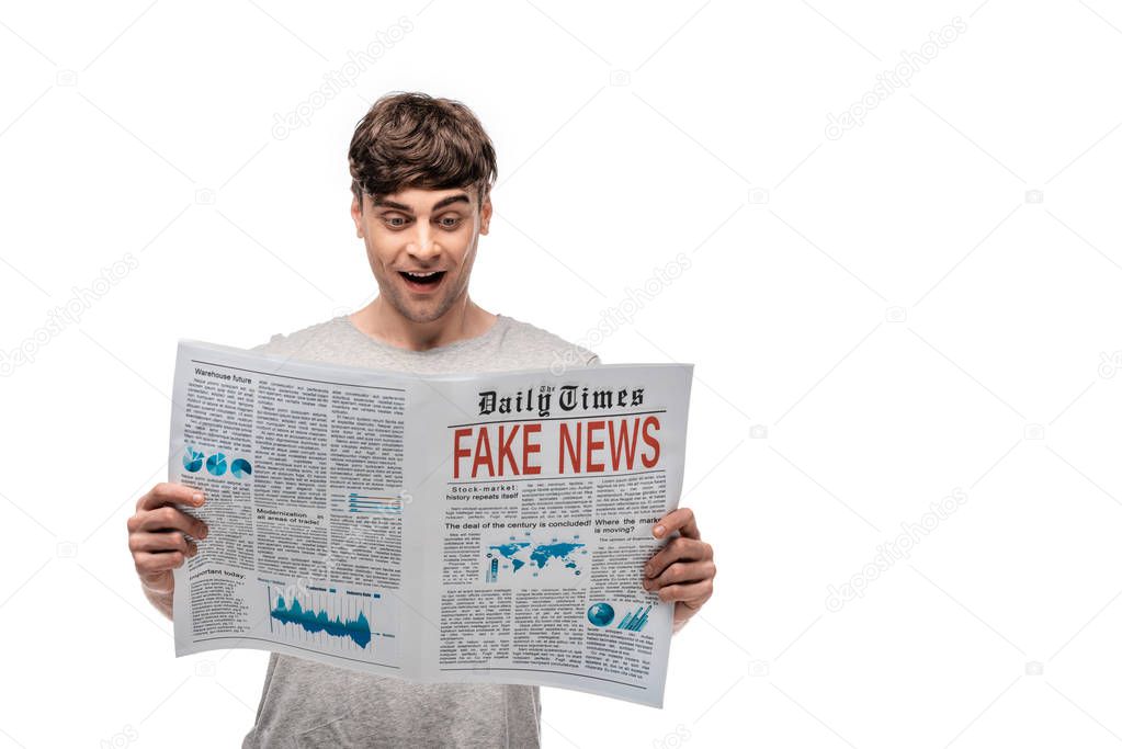 cheerful handsome man reading newspaper with fake news isolated on white