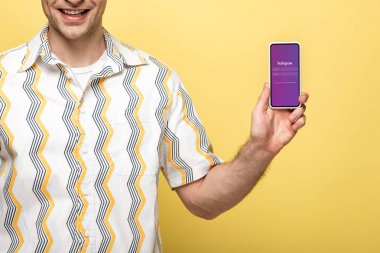 Kiev, Ukrayna - 16 Mayıs 2019: instagram uygulaması ile akıllı telefon gösteren gülümseyen adam kırpılmış görünümü, sarı izole