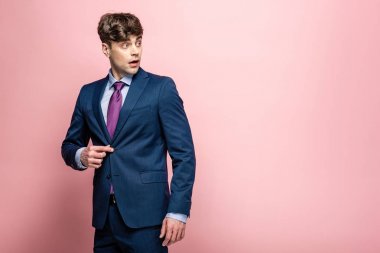 pembe arka plan üzerinde uzağa bakarak takım elbise yakışıklı, sürpriz işadamı