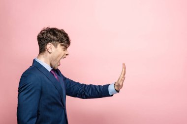 angry businessman quarreling and showing stop gesture on pink background clipart
