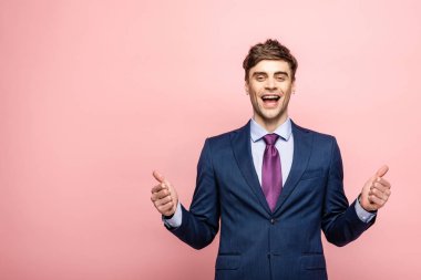 yakışıklı işadamı kameraya gülümseyen ve pembe arka plan üzerinde başparmak gösteren