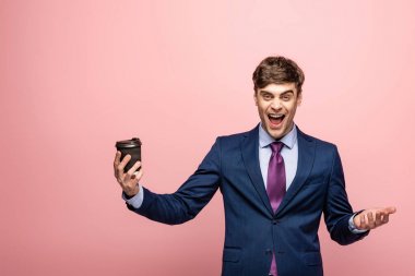 pembe arka planda kameraya gülerken gitmek için kahve tutan heyecanlı işadamı