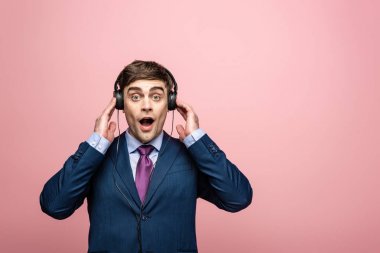 pembe izole kulaklıklar müzik dinlerken kamera bakarken sürpriz işadamı