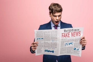 shocked businessman reading newspaper with fake news on pink background clipart