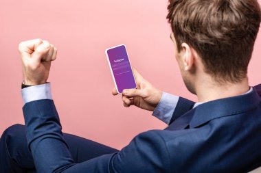 Kiev, Ukrayna - 16 Mayıs 2019: başarılı işadamının instagram uygulaması yla akıllı telefon kullanarak kırpılmış görünümü, pembe üzerinde izole