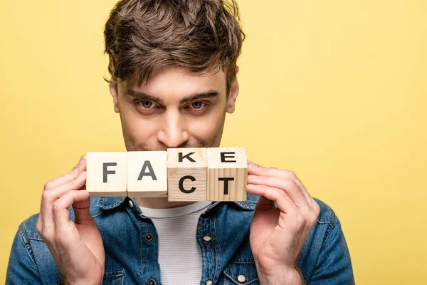 Positiver Junger Mann Blickt Die Kamera Während Holzwürfel Mit Gefälschtem — Stockfoto