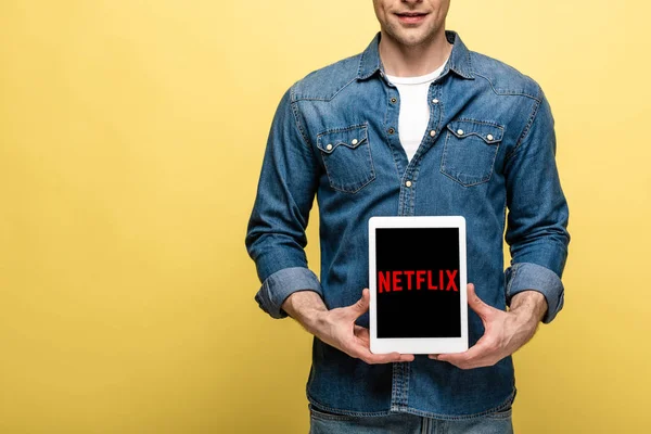 キエフ ウクライナ 2019年5月16日 ジーンズの服を着た男性のトリミングビューは Netflixアプリでデジタルタブレットを示し 黄色に隔離 — ストック写真