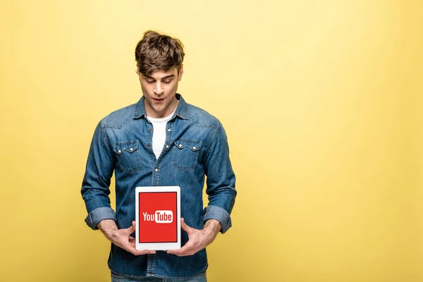 キエフ ウクライナ 2019年5月16日 ジーンズの服を着たハンサムな男性がYoutubeアプリでデジタルタブレットを見て 黄色に隔離 — ストック写真