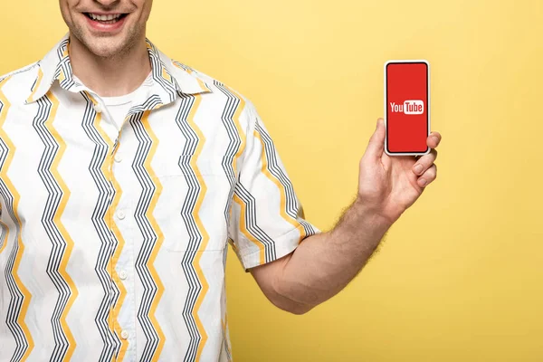 キエフ ウクライナ 2019年5月16日 黄色に隔離されたYoutubeアプリでスマートフォンを示す笑顔の男のトリミングビュー — ストック写真