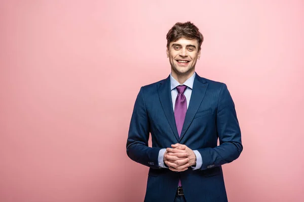 ピンクの背景にカメラで微笑むスーツの陽気なビジネスマン — ストック写真