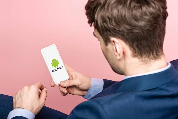 キエフ ウクライナ 2019年5月16日 ピンクに隔離されたアンドロイドアプリでスマートフォンを使用してビジネスマンのトリミングビュー — ストック写真