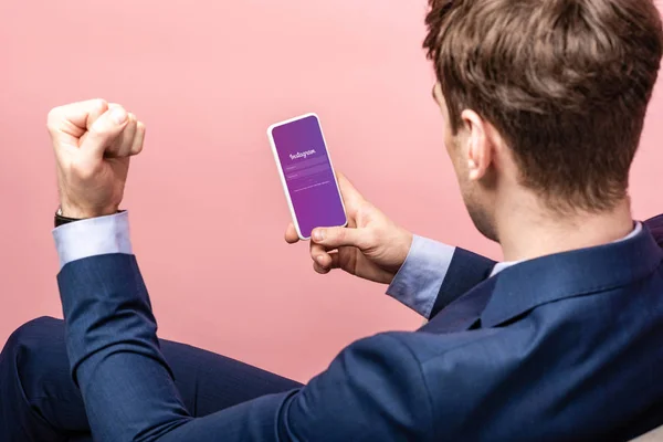 キエフ ウクライナ 2019年5月16日 ピンクに隔離されたInstagramアプリでスマートフォンを使用して成功したビジネスマンのトリミングビュー — ストック写真