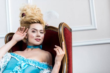 antika sandalyede oturan mavi elbiseli neşeli viktorya kadın 