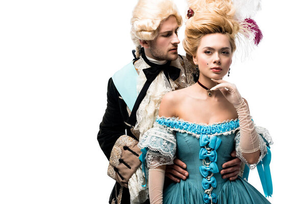 pompous victorian woman standing in blue dress and looking at camera near handsome gentleman isolated on white  