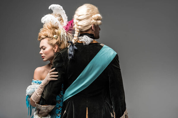 красивая викторианка обнимает джентльмена в парике на сером
