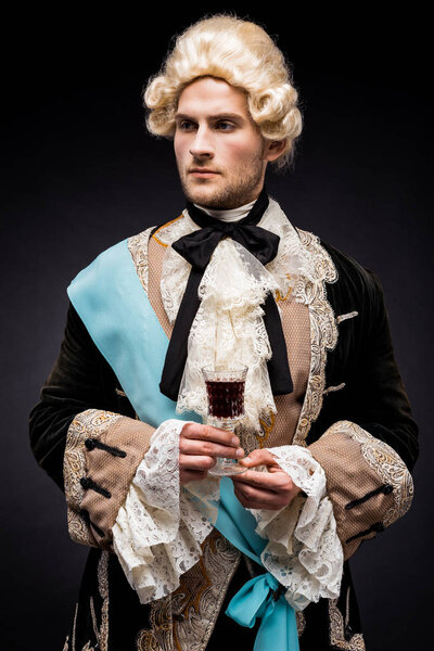 handsome victorian man in wig holding wine glass on black 