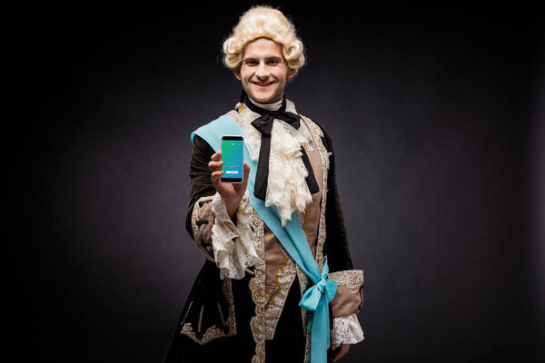 КИЕВ, УКРАИНА - 5 ИЮНЯ 2019 года: веселый победитель мужчина держит смартфон с приложением twitter на экране на черном
 