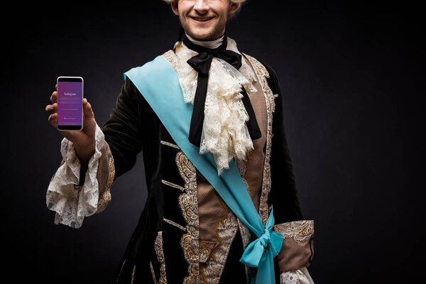 KYIV, UKRAINE - JUNE 5, 2019: cropped view of victorian man holding smartphone with instagram app on screen on black 