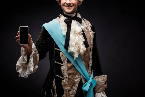 cropped view of happy victorian man holding smartphone with blank screen on black