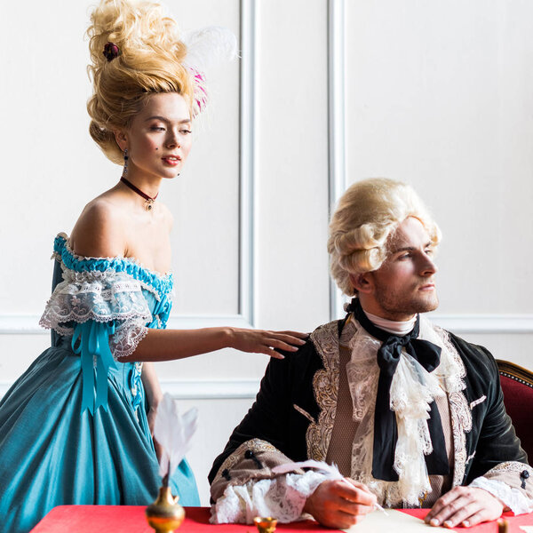 selective focus of attractive victorian woman touching shoulder of pompous man 