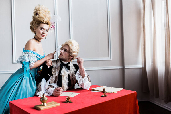 избирательный фокус веселой женщины-победительницы в парике, держащей веер рядом с красивым мужчиной
 