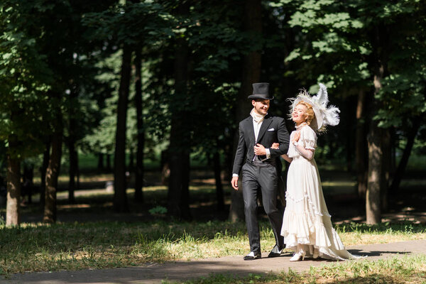 happy young victorian woman and handsome man in hat walking outside 