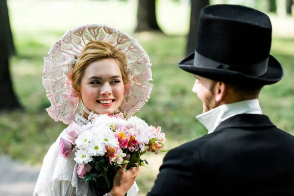 Foco Seletivo Mulher Vitoriana Feliz Segurando Flores Olhando Para Cavalheiro — Fotografia de Stock