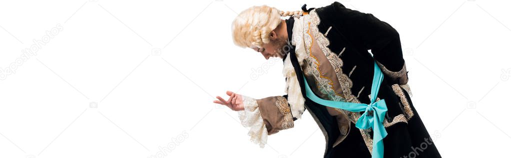 panoramic shot of handsome victorian gentleman in wig gesturing while bowing down isolated on white 