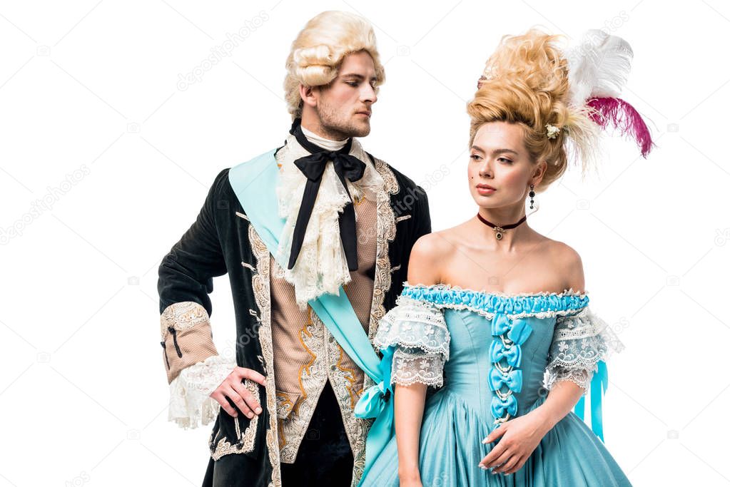 handsome man with hand on hip looking at beautiful victorian woman in blue dress isolated on white  