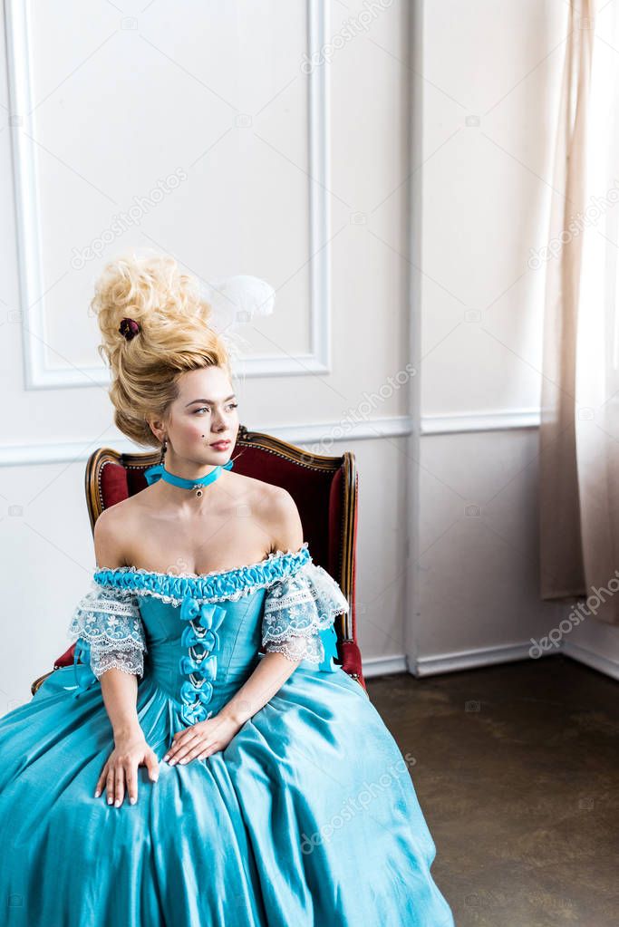 beautiful victorian woman in blue dress sitting on antique chair 