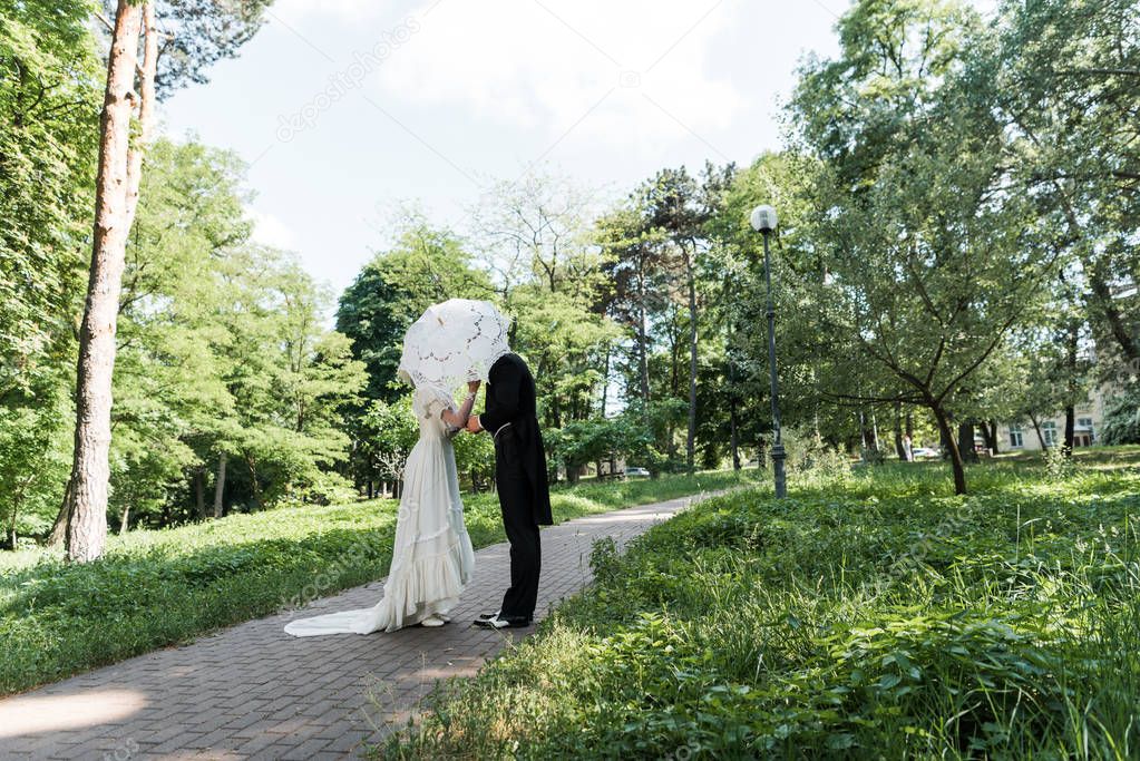 victorian man and woman covering faces while holding umbrella 