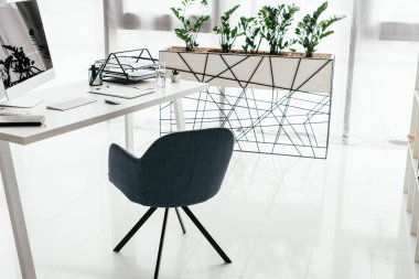 bilgisayar, belge tepsisi ve defter ofis sandalyesi ve bitki ile saksı yakınında beyaz masa