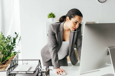 hamile kadın masa yakın ayakta, bilgisayarda çalışma ve akıllı telefonda konuşmak