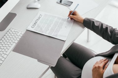 ofiste otururken belge imzalayan kadının kırpılmış görünümü