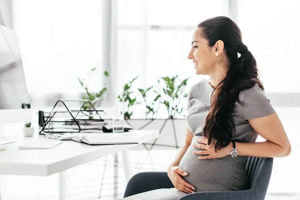 Vista Lateral Mujer Embarazada Sentada Silla Oficina Detrás Mesa Con —  Fotos de Stock