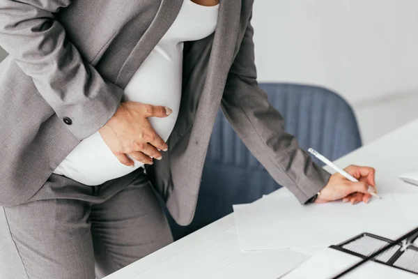 Vista Recortada Mujer Embarazada Traje Sosteniendo Vientre Tomando Notas Cuaderno — Foto de Stock