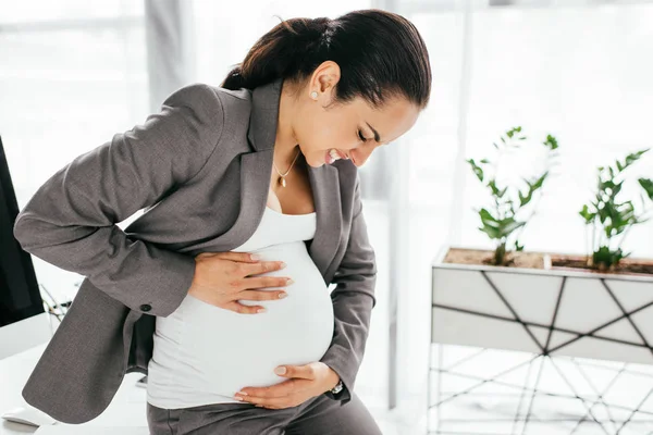 Kobieta Ciąży Trzyma Brzuch Grimace Powodu Bólu Siedząc Biurze — Zdjęcie stockowe