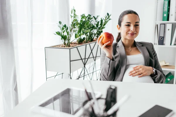 Pregnant Woman Holding Apple Looking Away Smiling While Sitting Table — Stock Photo, Image